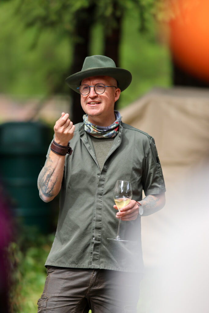 Guest Chef mit Weinglas bei Fire, Nature & Fine Dining im Val Bever, St. Moritz Gourmet Festival 2026