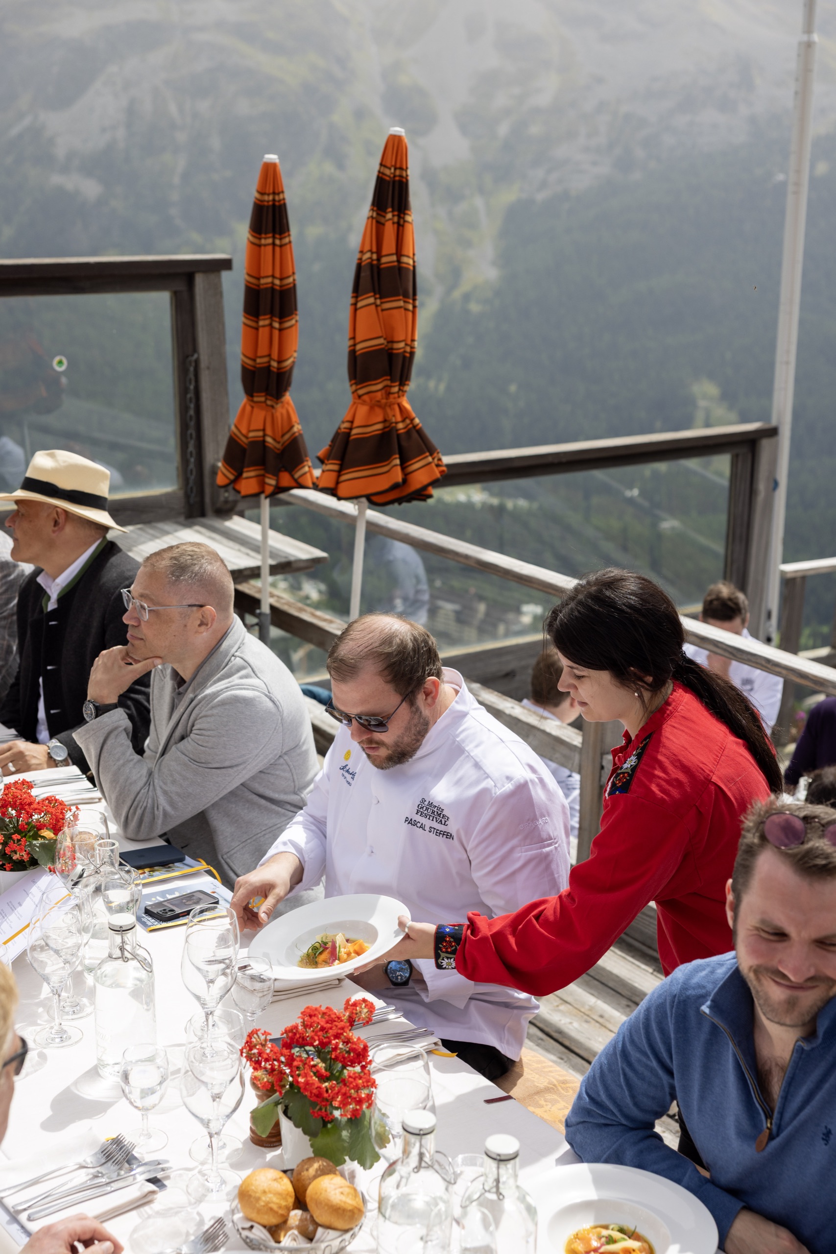 Köche und Gäste an der langen Tafel beim Chefs Lunch auf der Terrasse