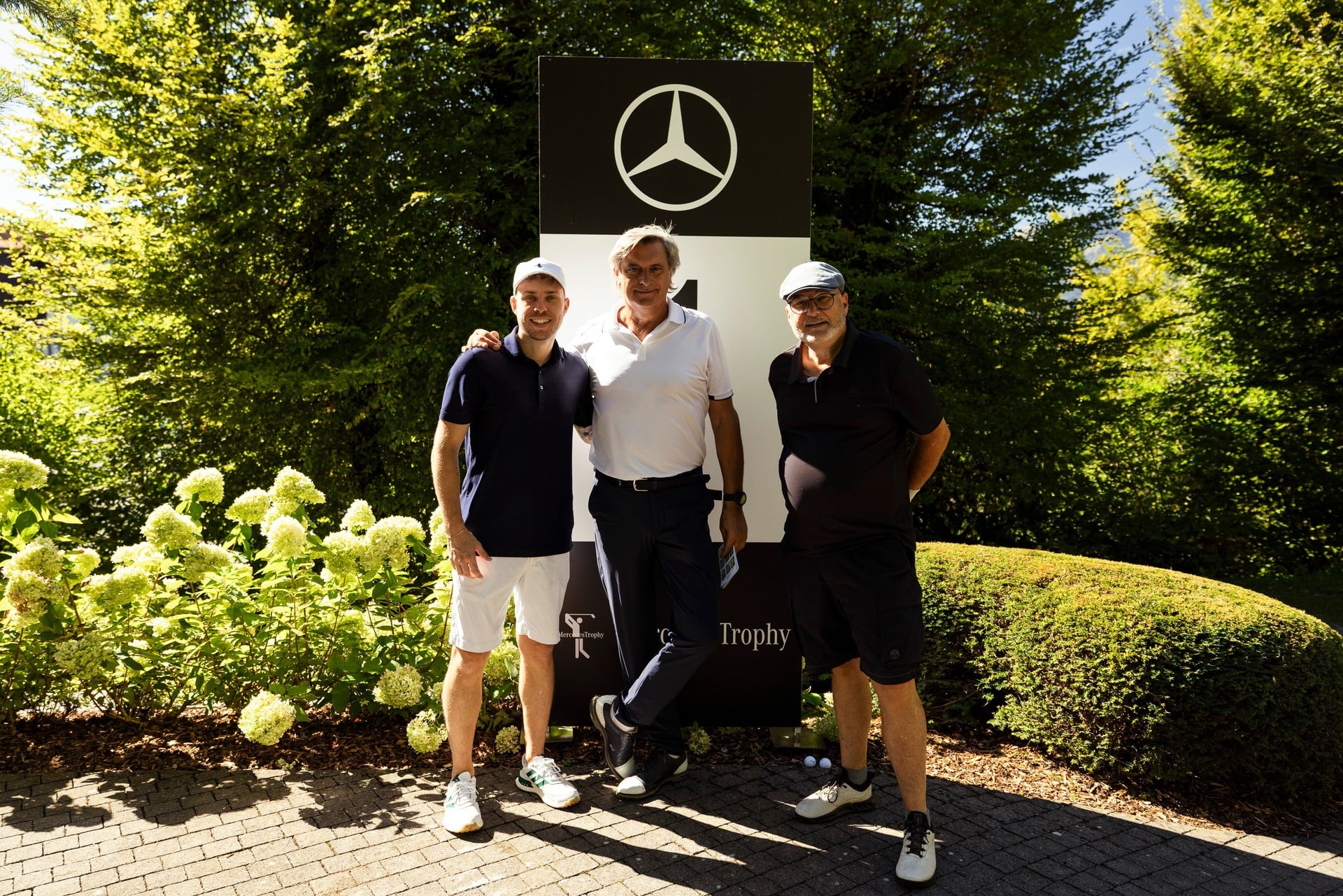 Three finalists with a golf bag at the MercedesTrophy photo wall, Swiss Final 2026